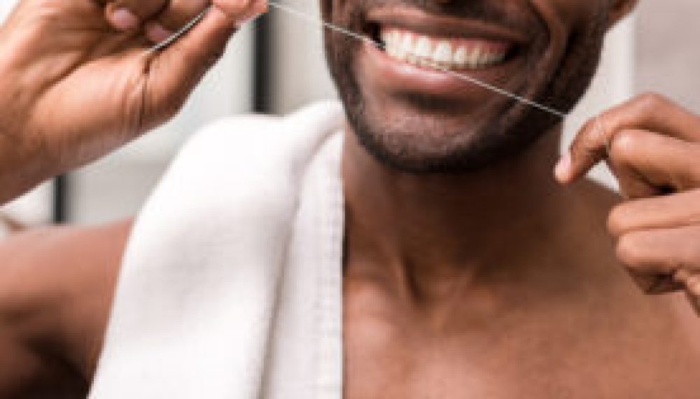 cropped shot of young man cleaning teeth with dental floss cropped shot of young man cleaning teeth with dental floss