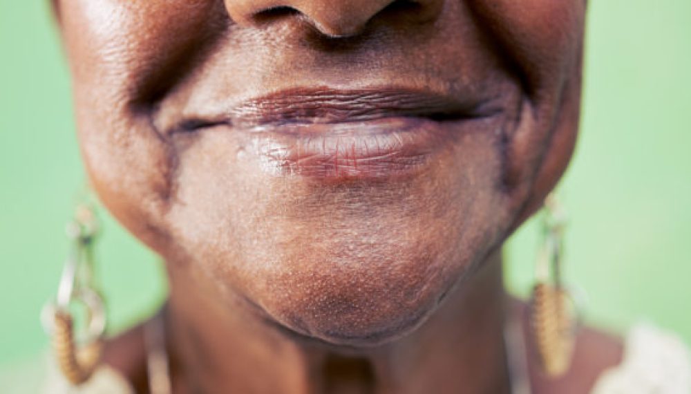 Old black woman, close-up of eye and face on green background. Old black woman portrait, close-up of eye and face on green background. Copy space